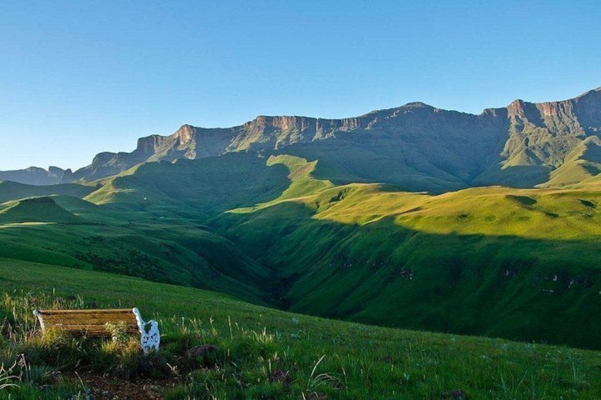 A grassy valley with rolling hills and a wooden bench. 3