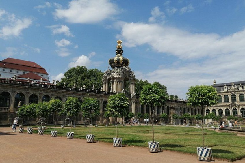 A large, ornate building with a central dome and a statue on top, surrounded by a well-maintained lawn and trees. 5