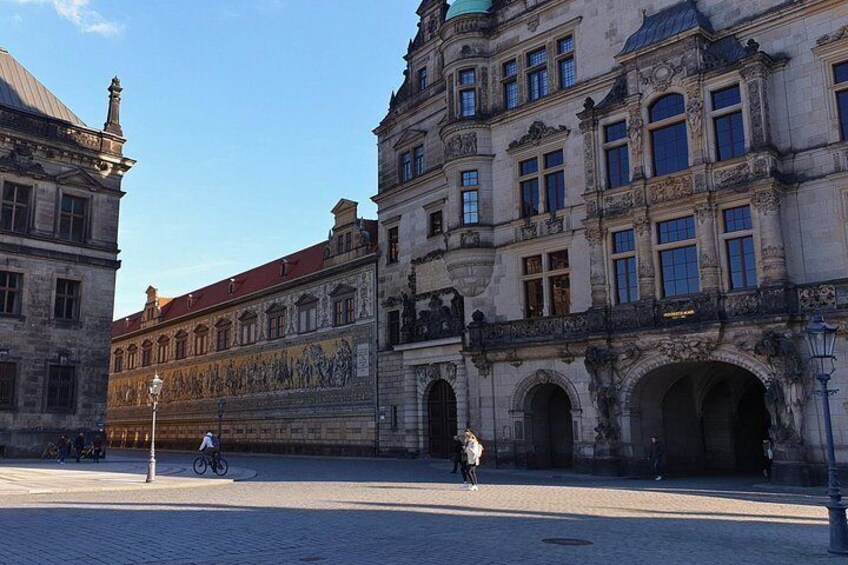 A historic building with ornate architecture, a cobblestone street, and a cyclist. 2