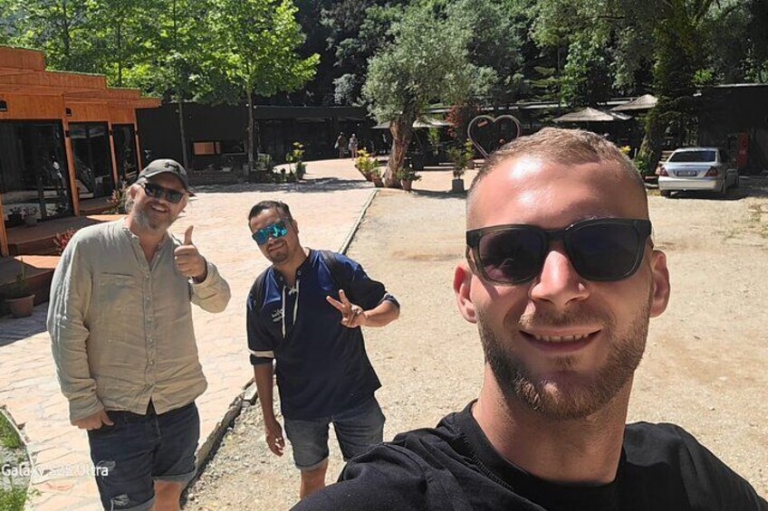 Three people standing outdoors with a patio area and trees in the background. 3