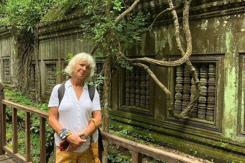 Une femme se tient sur un pont en bois, avec un bâtiment historique en arrière-plan. 5