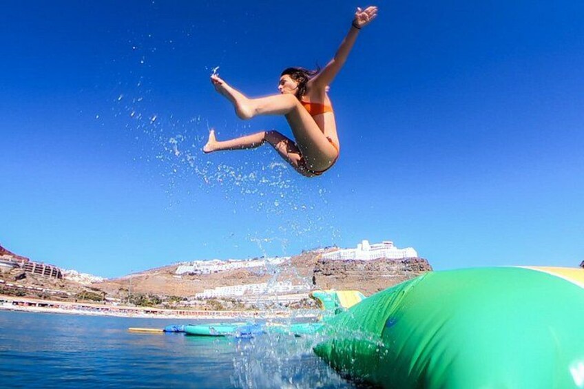 A person jumping into a body of water with a green inflatable in the foreground. 3