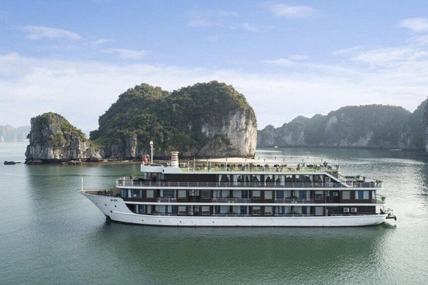 A large white river cruise ship with multiple decks, surrounded by calm water and limestone cliffs. 2
