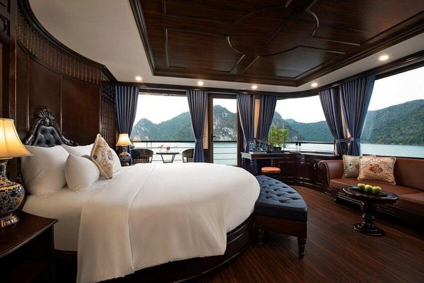 A luxurious bedroom with a large bed, a sofa, and a dining area with a view of mountains. 1