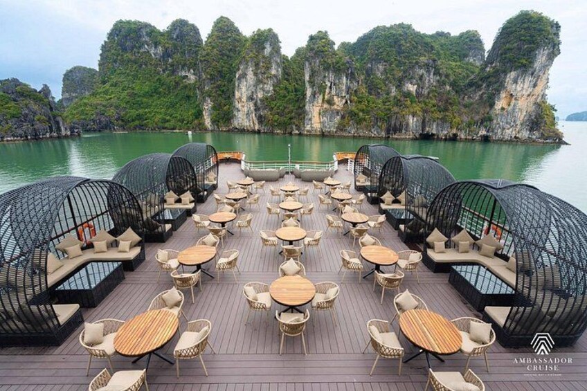 Une terrasse dotée de tables et de chaises, entourée de formations rocheuses naturelles et d’eau. 3
