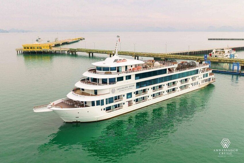 Een groot wit cruiseschip afgemeerd aan een steiger, met een gele veerboot op de achtergrond. 4