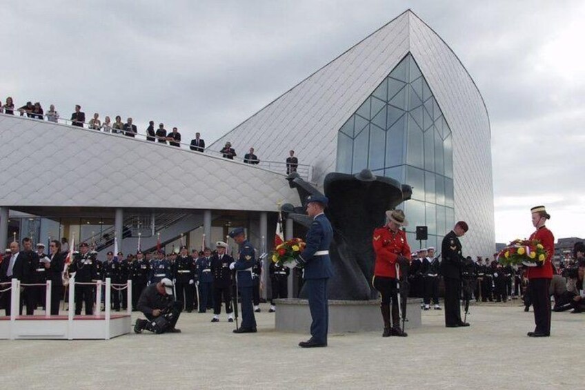 En högtidlig ceremoni med militär personal, en stor skulptur och en modern byggnad. 3