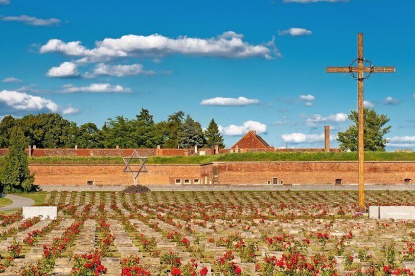 A cemetery with red flowers, a wooden cross, and a Star of David. 1