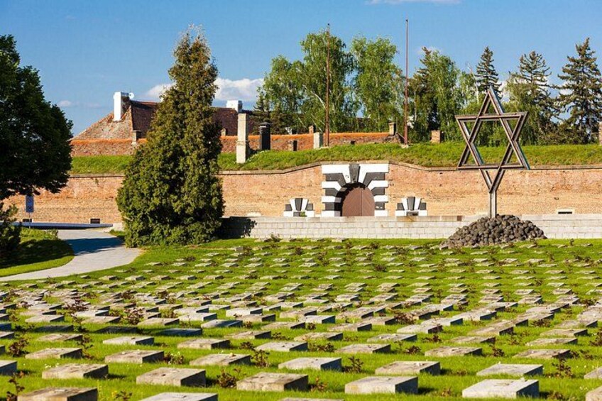 A cemetery with headstones, a Star of David, and a building in the background. 2