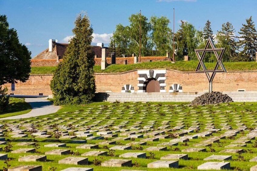 A cemetery with rows of graves, a Star of David, and a building in the background. 3