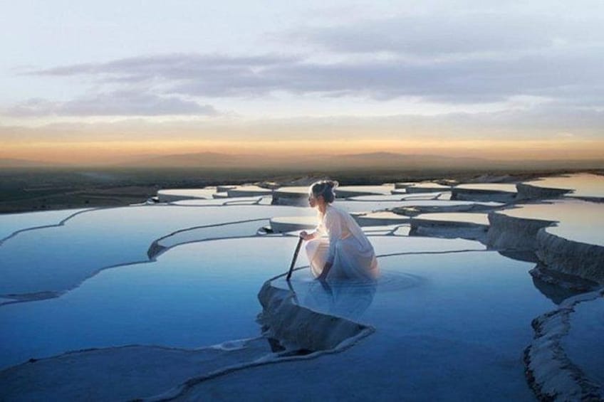 Une personne assise sur une terrasse aménagée, avec des bassins d’eau. 2