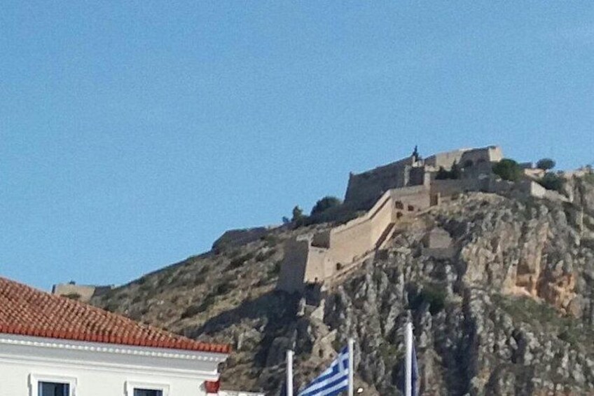 Una estructura fortificada en una colina, con un edificio de techo a tejas en primer plano. 4