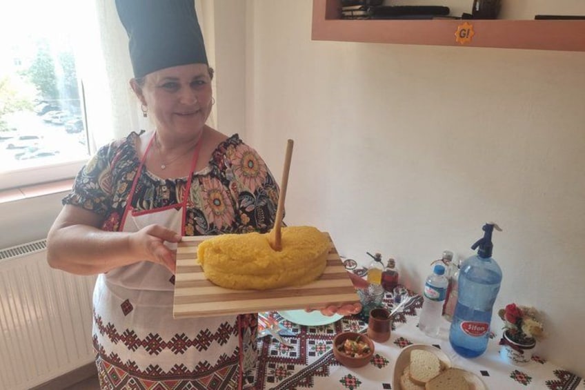 Une personne tenant un objet jaune avec un bâton, debout dans une cuisine où l’on peut voir une table, des bouteilles et une fenêtre. 3