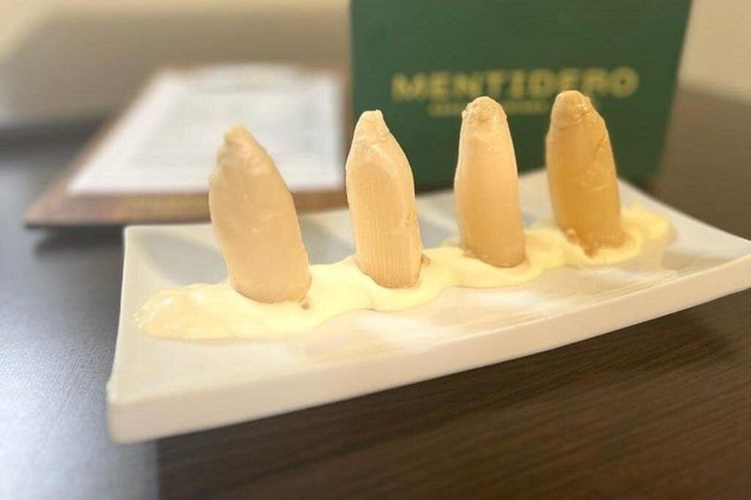 Un piatto bianco con quattro oggetti cilindrici e, sullo sfondo, una scatola verde con la scritta 'MENTIDERO'. 5