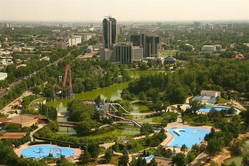 A theme park with roller coasters, pools, and a large building in the background. 5