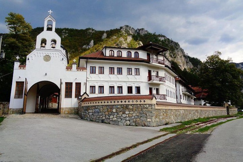 A white church with a bell tower, a stone wall, and a mountain backdrop. 3