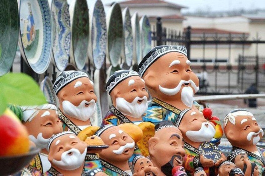A group of statues with traditional attire and white beards, displayed outdoors with a fence and buildings in the background. 4