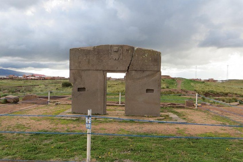 Una construcción de piedra grande con dos portales, rodeada de campos verdes y un cielo nublado. 4
