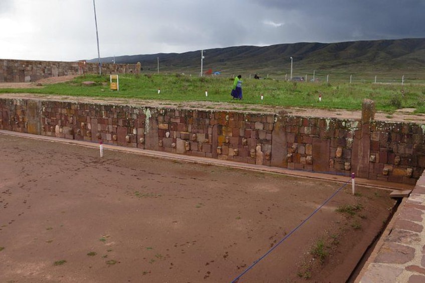 Un muro de piedra, un campo cubierto de hierba y un paisaje montañoso. 5