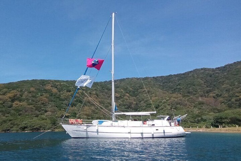 A sailboat on a calm lake with a forested hill in the background. 3
