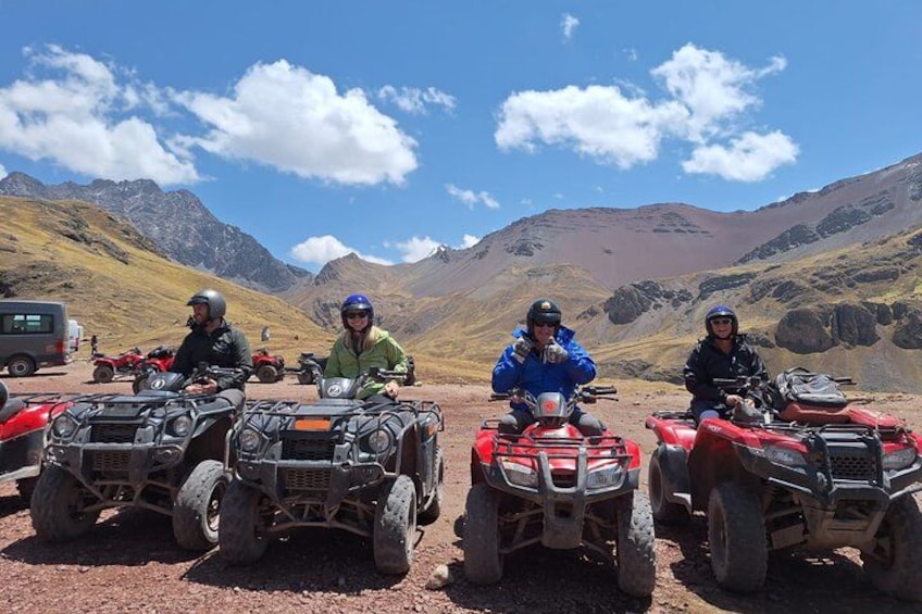 Vier personen op quadbikes in een bergachtig gebied, onder een heldere lucht. 3