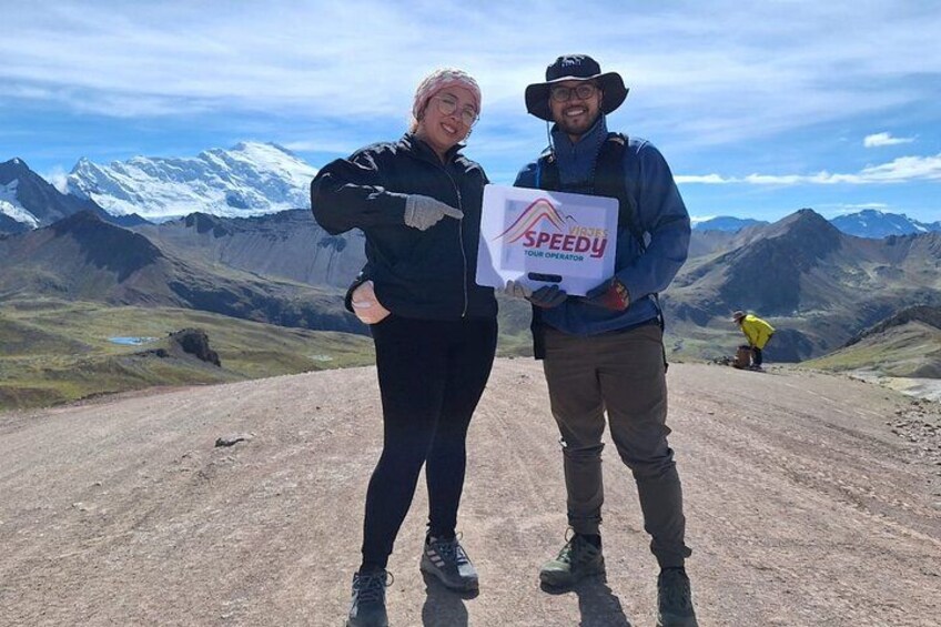 Two people standing on a dirt road with mountains in the background. 5
