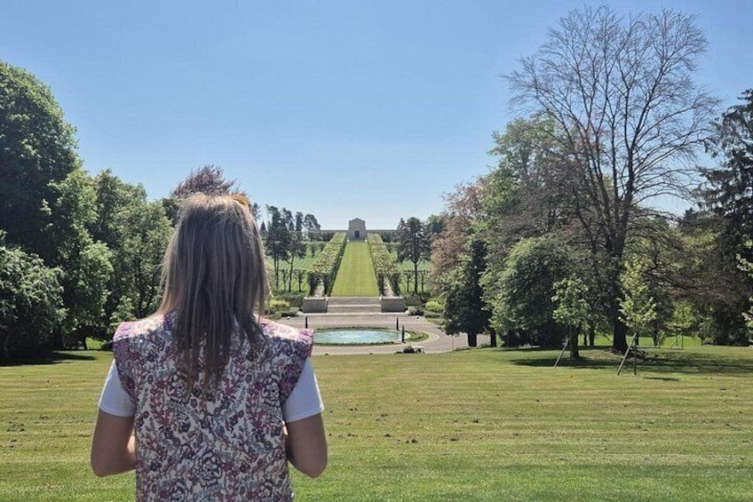 Una persona de pie en un parque con vistas a una colina y un estanque. 3