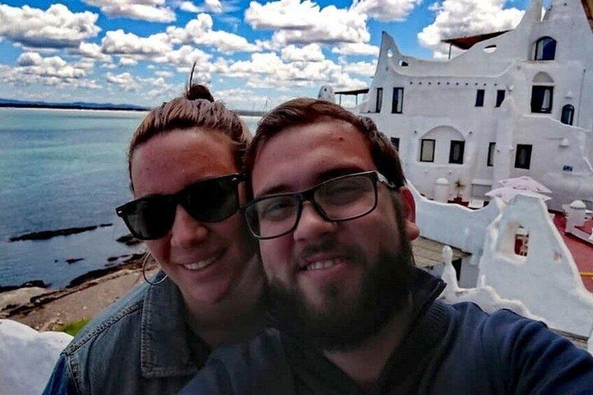 Two people taking a selfie with a white building and a body of water in the background. 2