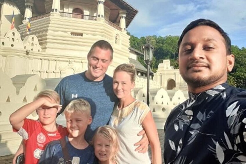Una familia frente a un edificio blanco con balcón y una bandera. 2
