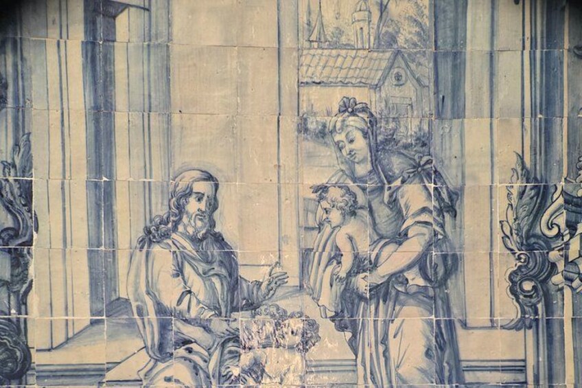 Una pared detallada con azulejos azules y blancos que representa una escena religiosa, con figuras y elementos arquitectónicos. 2
