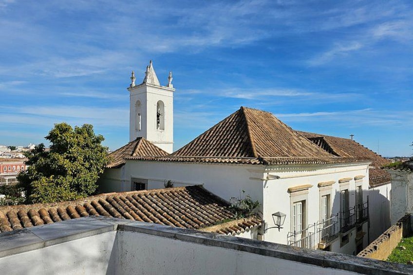 Une église blanche avec un clocher, des tuiles de toit en terre cuite et un ciel d’un bleu limpide. 3