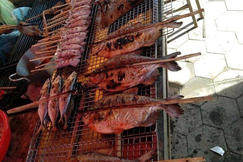 Grilled fish on a metal rack outdoors. 3