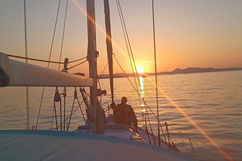 Un velero con dos personas en la cubierta durante el atardecer. 3