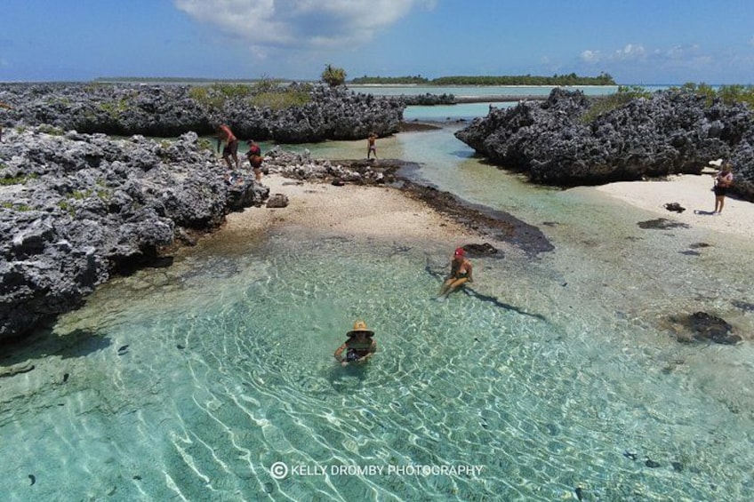 Une plage tropicale avec une eau turquoise et limpide, des formations rocheuses et des personnes pratiquant diverses activités nautiques. 5