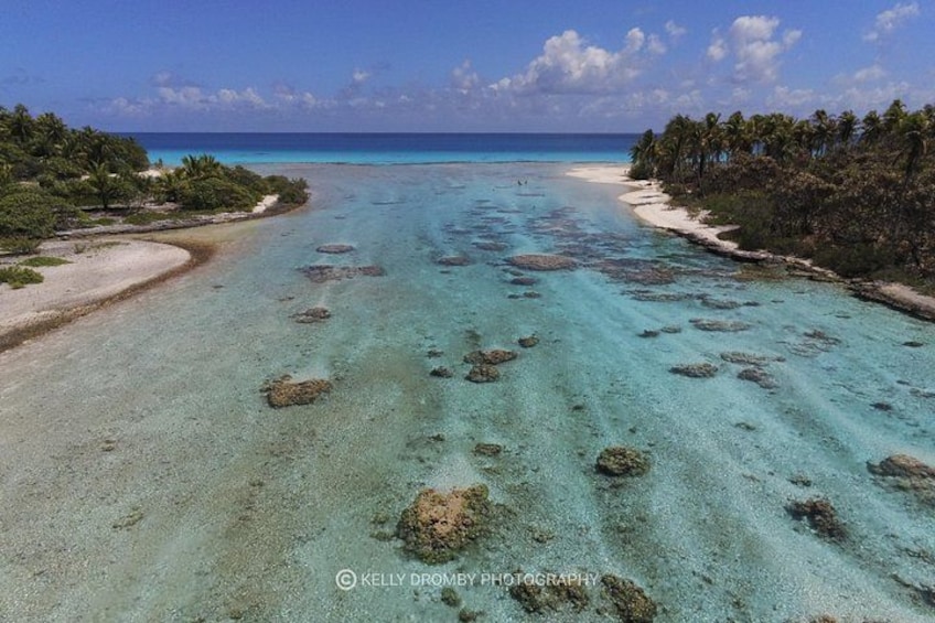 A tropical beach with clear turquoise waters, white sand, and scattered rocks. 3