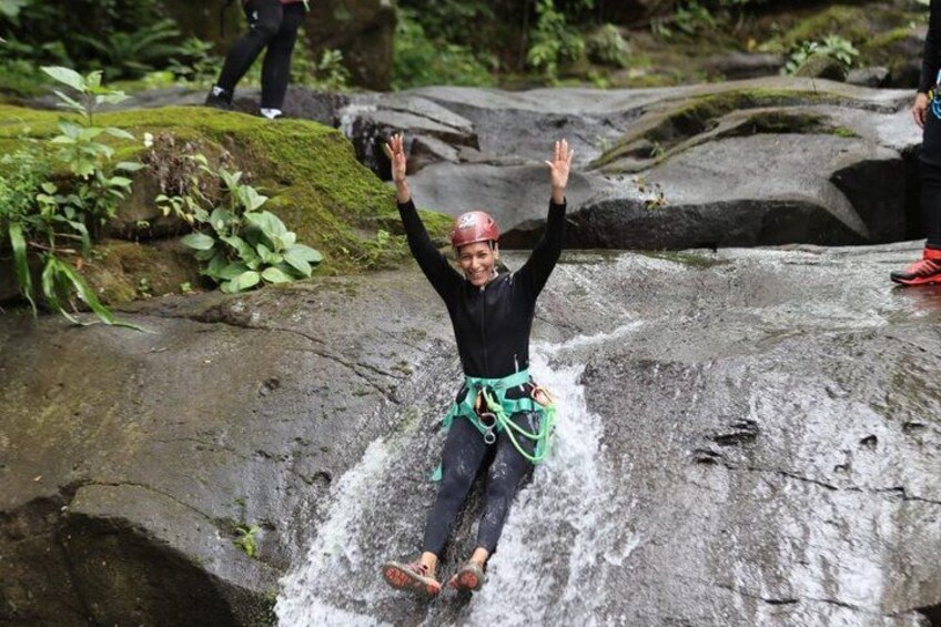 A person rappelling down a large rock with a harness and ropes. 4