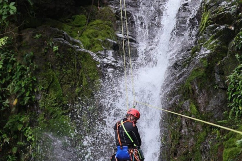 A person rappelling down a waterfall with a harness and ropes. 2