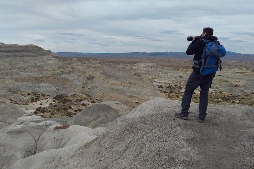 Una persona con macchina fotografica e zaino in piedi su un terreno roccioso. 2