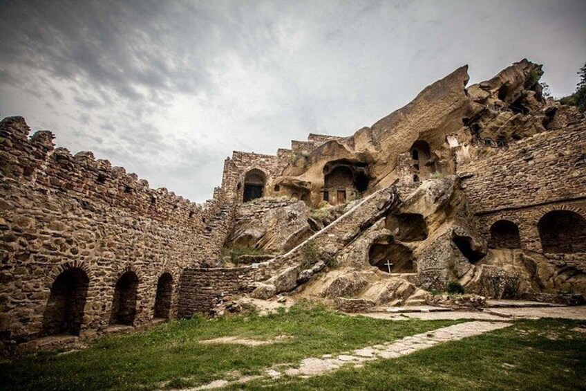 Ancient stone ruins with arched doorways and a staircase leading up to a building. 4