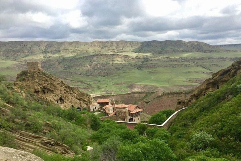 A valley with a small building and a watchtower on a hill. 2