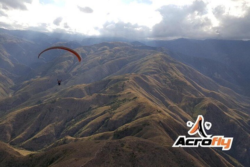 Una persona practica parapente sobre un paisaje montañoso. 1