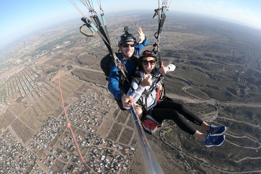 A person paragliding over a landscape with fields and a distant town. 1