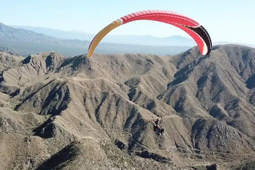 A person paragliding over a mountainous landscape. 5