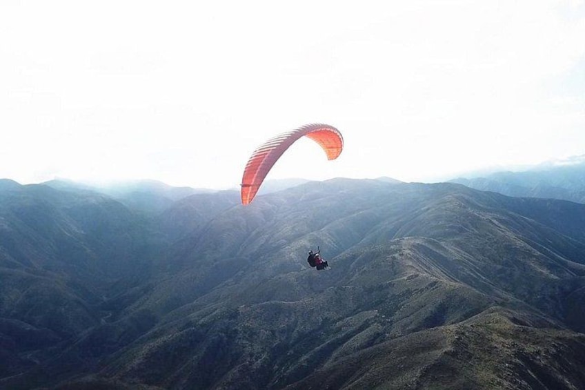 A person paragliding over a mountainous landscape. 2