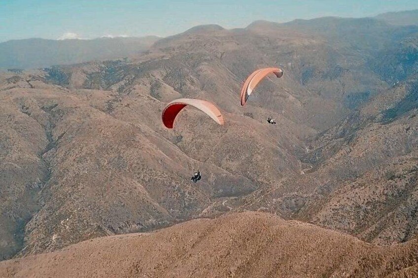Two paragliders flying over a mountainous landscape. 3