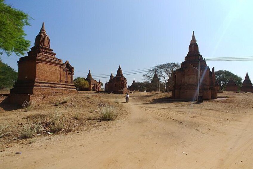 A dirt road with ancient brick structures and trees in the background. 4