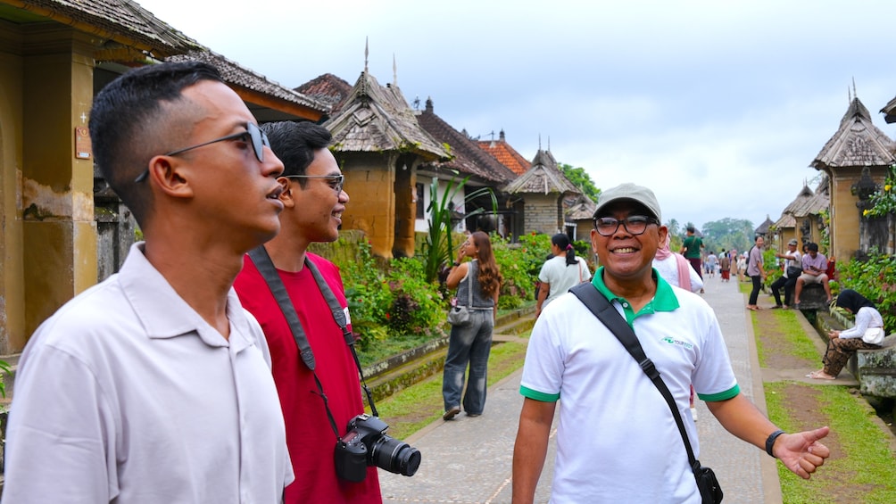 A group of people walking along a pathway with traditional buildings in the background. 1