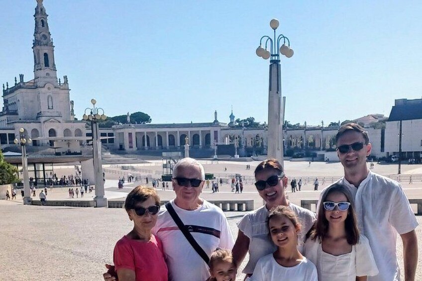 A group of people in front of a historic building with a tall tower and a fountain. 5