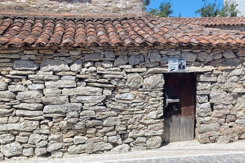 A stone building with a tiled roof and a wooden door. 2