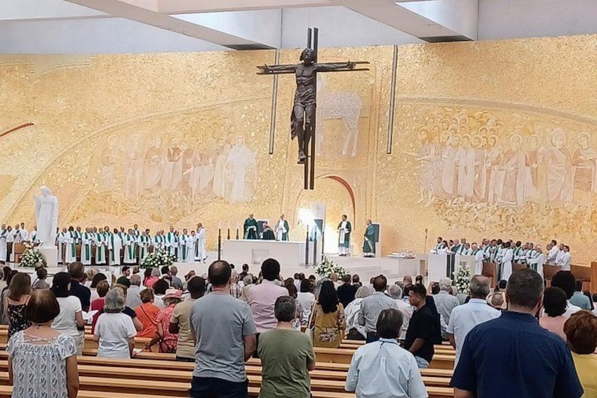 A church interior with a large crucifix, altar, and congregation. 4